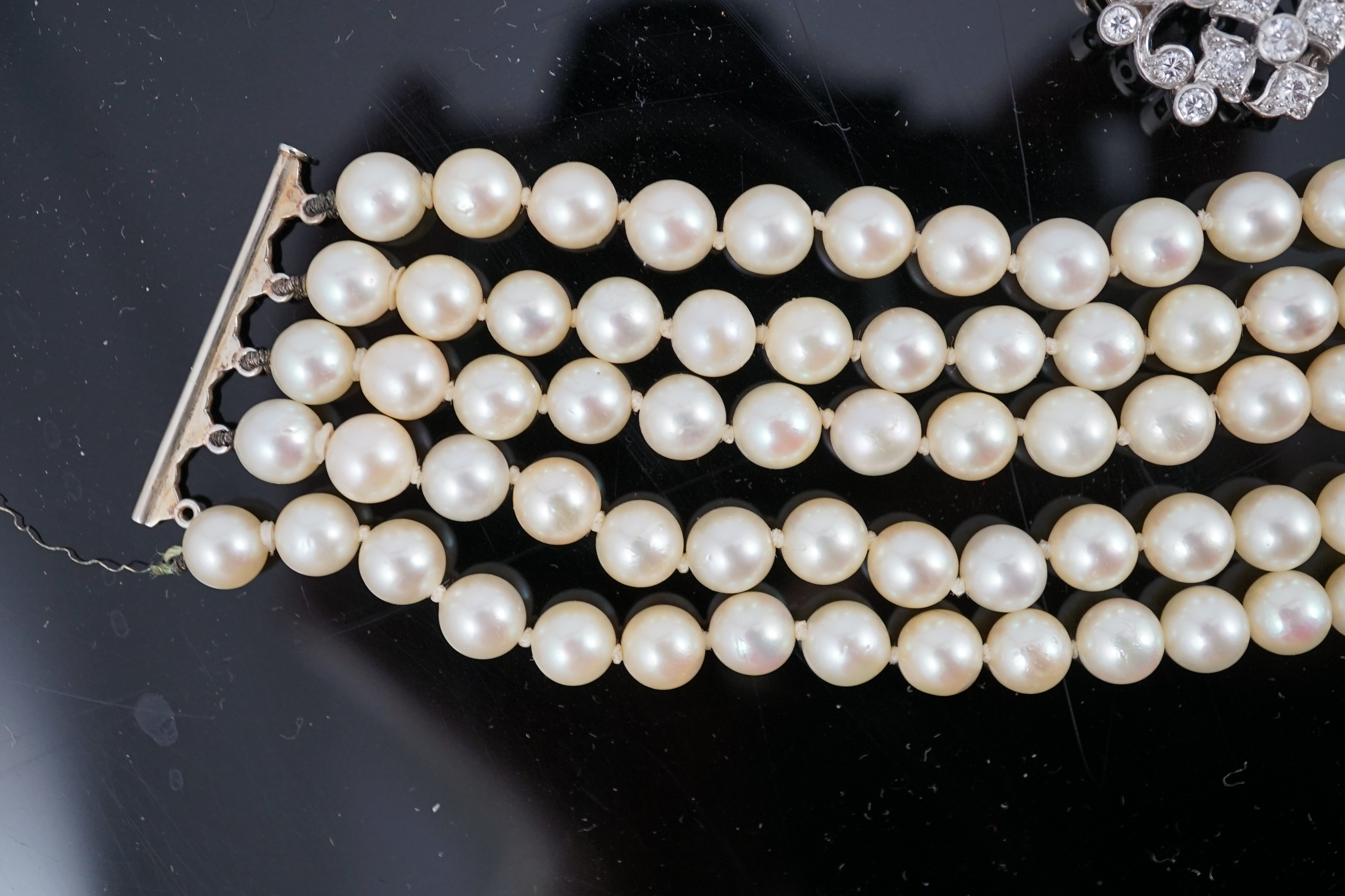 A mid 20th century quintuple strand cultured pearl choker necklace, with diamond cluster set white gold clasp and diamond cluster set white gold scrolling central motif, together with a matching bracelet